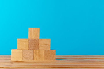 Stacked wooden blocks on wooden desk against blue background