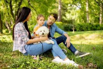 Naklejka na ściany i meble Beautiful happy family is having fun with bichon dog outdoors