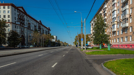 A wide city street with tram lines going into the distance. City landscape.
