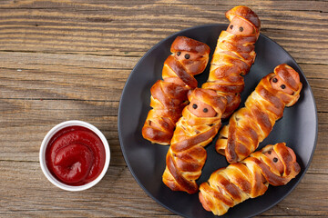 Scary sausage mummies in dough for kids party. Funny crazy Halloween food for children.