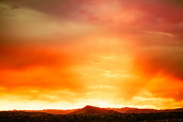 Naklejka na ściany i meble A dramatic cloudy sunset in the desert of Arizona with mountains.