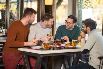 Fototapeta na wymiar Friends eating burgers and drinking beer in pub