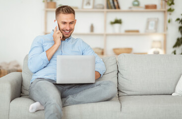 Portrait of successful smiling guy using phone and pc