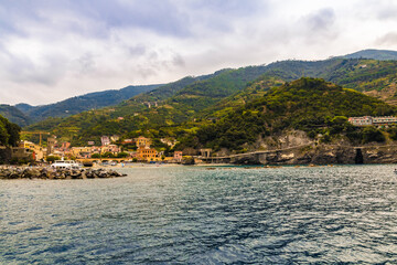 Gorgeous panoramic landscape view from the sea, overlooking the sand beach, the colourful buildings and the hillside of the old part of Monterosso al Mare in the Cinque Terre coastal area.