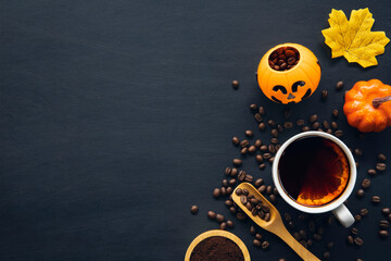 halloween decoration with hot coffee and beans on dark background. flat lay. Copy space for text.
