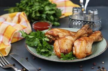 Chicken drumsticks, baked in marinade of ketchup, soy sauce and balsamic vinegar on a plate on dark background, horizontal format
