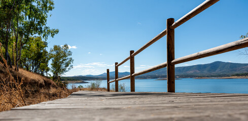 Walkway with railing towards the edge of a reservoir, focus on the horizon