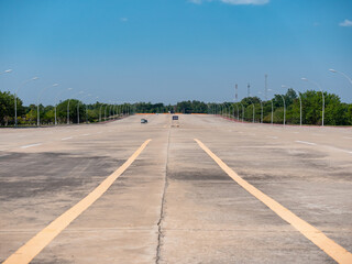 Fototapeta na wymiar A single car on the deserted 20 lane highway in the empty new capital Naypyidaw in Myanmar (Burma)