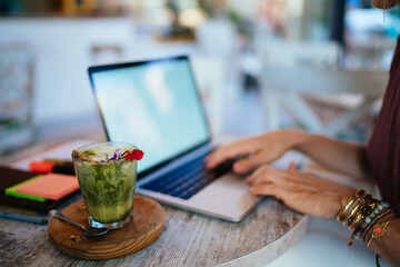 Woman using laptop in cafe during breakfast