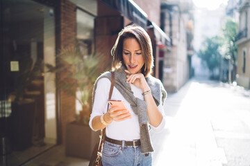 Fototapeta premium Serious businesswoman surfing smartphone on empty sidewalk