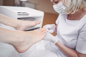 Pedicurist doing professional medical pedicure procedure in beauty salon with special eguipment....