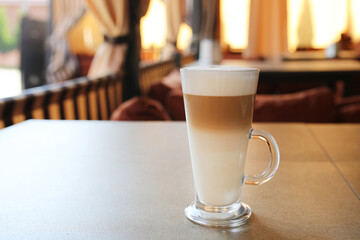 A cup of latte. Coffee day. A glass of coffee. Cafe with milk. Hot drink in the cafe. Latte in a glass.
