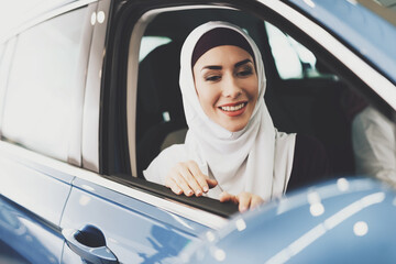 Fototapeta premium Arab woman sits in new car and looks out of window