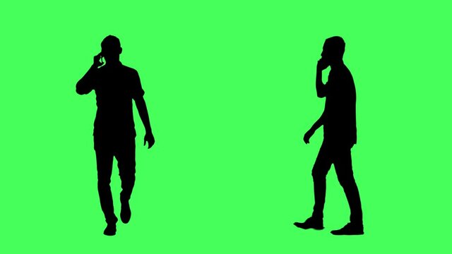 Silhouettes of business man walking and talking on cell phone. Front and side view. Full body on green screen chroma key background.