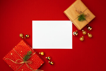 Blank sheet of paper and wrapped present for Christmas celebration on red background