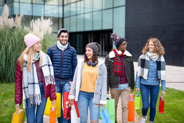 Obraz premium friends walking around the city during the sales period, multiracial group of happy and smiling young people after buying gifts, bright color filter