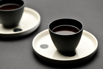 Strong coffee served in ceramic cups over black background
