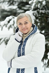 Happy beautiful senior woman posing in snowy winter park