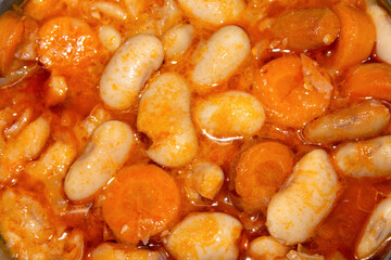 Baked giant beans with chopped carrots and tomato sauce. Greek traditional food. Selective focus