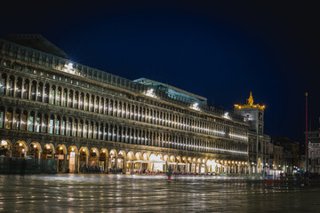 Fototapeta na wymiar Olivetti exhibition centre on piazza San Marco in Venice, Italy during a rainy night time, with reflections on the floor.