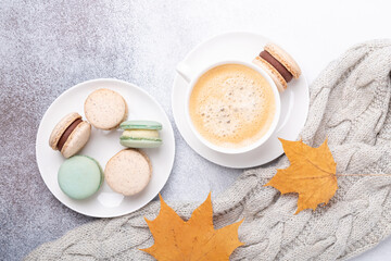 Obraz na płótnie Canvas Cozy autumn composition with sweater, coffee, various macaron and yellow maple leaves on stone background. Flat lay, top view