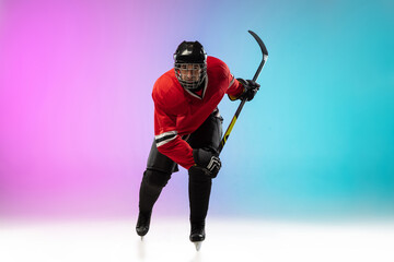On fire. Male hockey player with the stick on ice court and neon gradient background. Sportsman wearing equipment, helmet practicing. Concept of sport, healthy lifestyle, motion, wellness, action.
