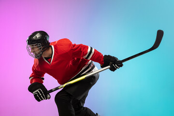 On fire. Male hockey player with the stick on ice court and neon gradient background. Sportsman...
