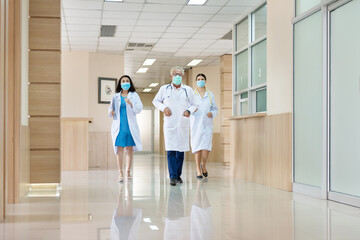 Three doctors with mask running in a lobby. Doctors rushing for emergency in hospital. Moving...