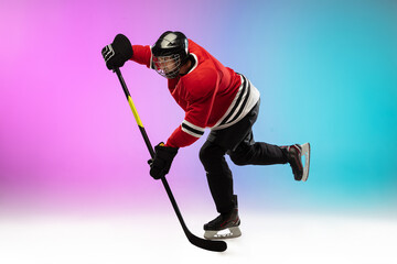 First. Male hockey player with the stick on ice court and neon gradient background. Sportsman wearing equipment, helmet practicing. Concept of sport, healthy lifestyle, motion, wellness, action.