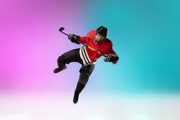 Fototapeta na wymiar In flight. Male hockey player with the stick on ice court and neon gradient background. Sportsman wearing equipment, helmet practicing. Concept of sport, healthy lifestyle, motion, wellness, action.