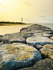 Lighthouse with ocean line horizon and stones bay