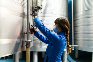 young woman technician from the wine cellar taking a sample for analysis 