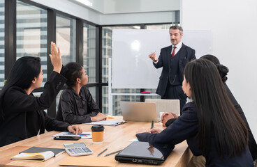 Asian businesswoman raising hand and asking questions and discussing to businessman during team business meeting in modern office.