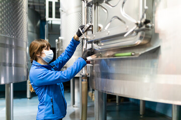 young woman technician from the wine cellar taking a sample for analysis 
