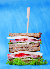 Multilayered club sandwich with cheese, pork balyk, bell pepper, lettuce leaves and toasted bread...