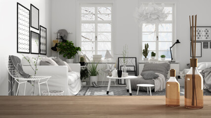 Wooden table top or shelf with aromatic sticks bottles over scandinavian black and white living room with sofa, armchair, carpet and decors, side tables, architecture interior design