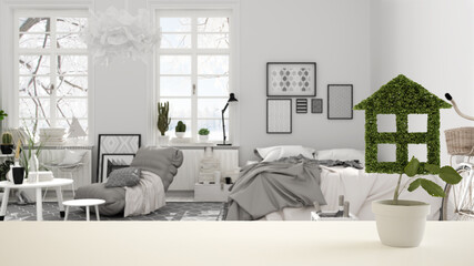 White table top or shelf with green plant in pot shaped like house, scandinavian bedroom with double bed background, interior design, real estate, eco architecture concept idea