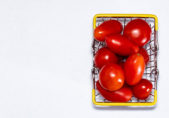 Naklejka na ściany i meble Shot of tomatoes in shopping basket on white background with copy space. Ripe tasty red tomatos in shopping basket. Top view. Copy space.