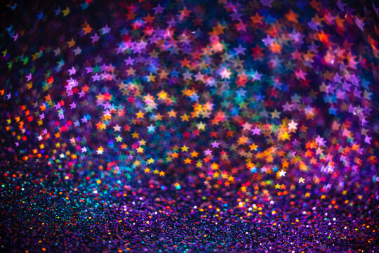 Decoration twinkle glitters background, abstract shiny backdrop with stars, modern design overlay with sparkling glimmers. Purple, blue and red backdrop glittering sparks with blur effect.