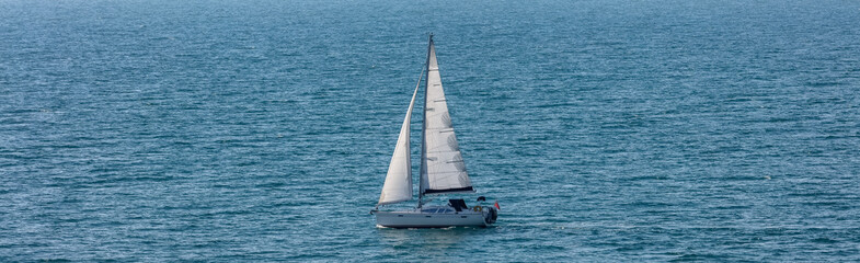 High angle shot of a white sailboat sailing in Weymouth Bay, UK