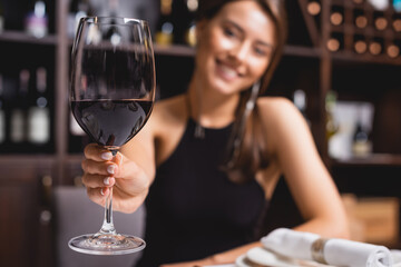 Selective focus of woman showing glass of wine in restaurant