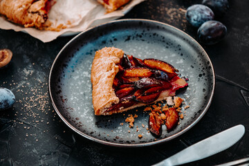  Piece of homemade biscuit with plums on a plate close-up