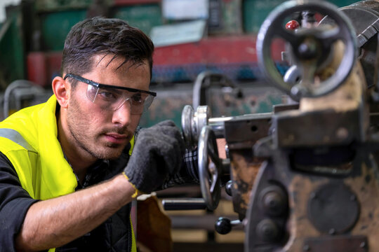 Engineer Or Supervisor Wearing Safety Glass And Glove, Concentrate On Adjusting The Gap Of The Milling (lathe) Machine At The Iron Manufacturing Factory. Heavy Sweating On His Face. Industrial Area..