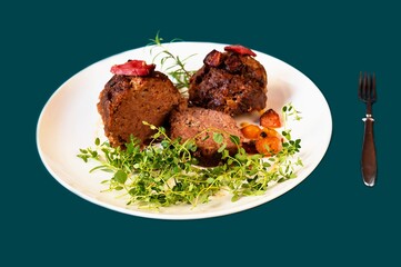 Baked meatloaf with herb twig on white plate, fork on green.