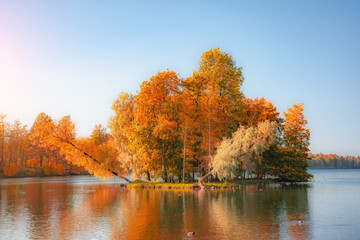 Island with autumn sloping trees in a large lake.