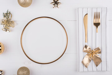 White plate with a gold border with Christmas decorations around it, New year's menu, festive table setting