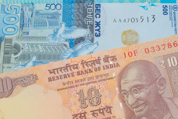 A macro image of a orange ten rupee bill from India paired up with a blue, plastic five hunded tenge bank note from Kazakstan.  Shot close up in macro.