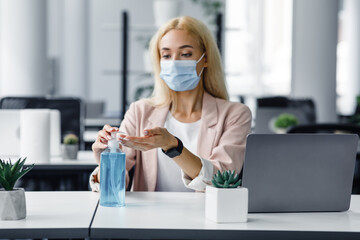 Safety and health protection at work in office. Millennial woman in protective mask with smart...