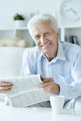 Fototapeta na wymiar Portrait of senior man reading newspaper at home
