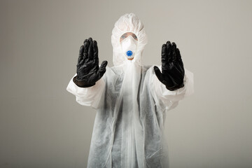 woman in protective medical suit wearing mask and gloves with hand gesture